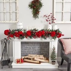 a fireplace decorated for christmas with red flowers and greenery