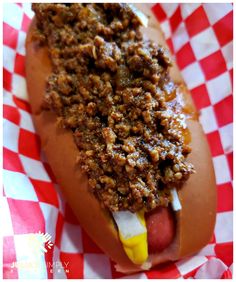 a chili dog with mustard and ketchup on a red and white checkered paper