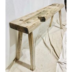 a wooden bench sitting on top of a white sheet covered floor next to a wall