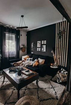 a living room with black walls and striped curtains on the windowsill, coffee table in front of couches