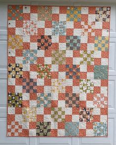 an orange and white quilt hanging from the side of a garage door with a blue handle