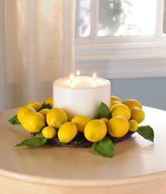 a white candle sitting on top of a table next to lemons