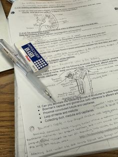 a pen is sitting on top of some papers with drawings and notes in front of it