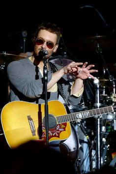 a man singing into a microphone while holding an acoustic guitar