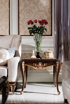 a table with flowers in a vase on top of it next to a couch and chair