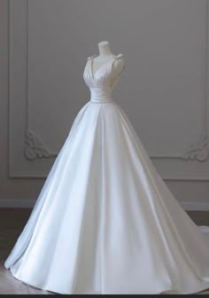 a white wedding dress on display in front of a wall