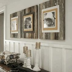 three framed pictures hang on the wall above a table with candles and other items in front of it