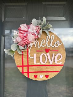 a wooden sign that says hello love hanging on a door with red and white ribbons