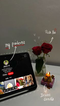 a tablet computer sitting on top of a table next to a vase filled with roses