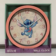 the clock has stitch on it's face and is in a green box with pink trim