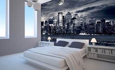 a bedroom with a large city skyline wall mural in black and white, along with two lamps on either side of the bed