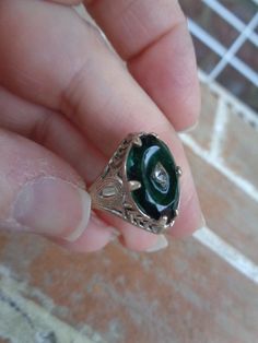 This is a vintage ring from a Berks county Pennsylvania estate. It is a size 7.5 and is sterling silver, but not marked. Has a green glass stone with a diamond chip in the middle. I have had different jewelry people tell me it looks Victorian and some say it is  from the 1960's and it is supposed to look older. Has a gold surface, but was probably dusted with gold. Nice condition.  Please don' t hesitate to ask questions. Happy collecting! Victorian Emerald Cut Jewelry For Formal Occasions, Victorian Emerald Cut Formal Jewelry, Art Deco May Birthstone Ring, Vintage Filigree Ring Jewelry, Antique Sterling Silver Ring, Victorian Green Ring As A Gift, Victorian Style Emerald Cut Jewelry For Anniversary, Vintage Oval Engraved Ring Stamped 925, Victorian Silver Jewelry With Emerald Cut