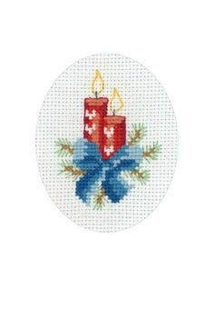 a cross stitch pattern with two lit candles on the front and blue ribbon around it