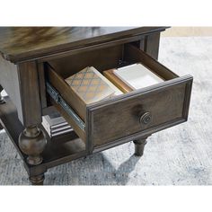 an open drawer with books and papers in it on a carpeted floor next to a lamp