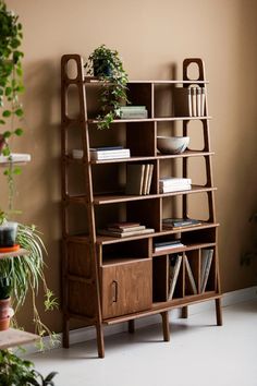 a book shelf with books and plants in it next to a wall mounted planter