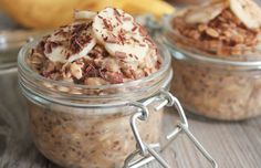 two glass jars filled with oatmeal and nuts on top of a wooden table