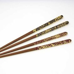 four wooden chopsticks with designs on them sitting next to each other in front of a white background