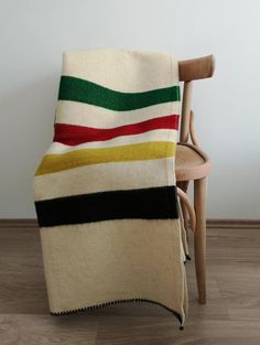 a chair with a blanket on it sitting in front of a white wall and wooden floor