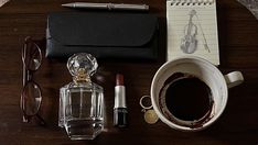 an assortment of items on a table including glasses, lipstick, pen and notepad