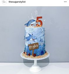 there is a cake that has been decorated to look like a shark and the number five on it