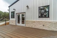 a white house with wooden decking and windows