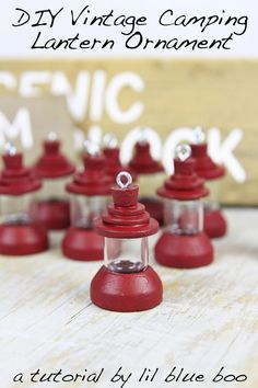 small red candles sitting on top of a wooden table with the words diy vintage camping lantern ornaments