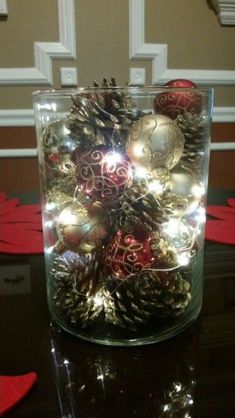 a glass vase filled with christmas ornaments on top of a table