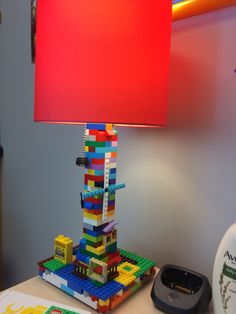 a lamp that is made out of legos on a table next to a phone