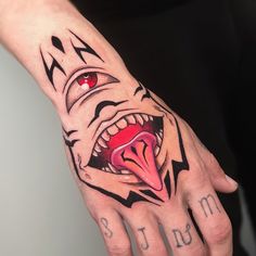 a person's hand with a tattoo on it that has an evil face and red eyes