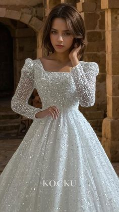 a woman in a white wedding dress with long sleeves and sequins on it