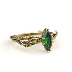 a gold ring with a green stone in the center and leaves on it's sides