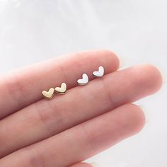 Tiny yet mighty, these heart stud earrings pack a stylish punch. Crafted from high-polish sterling silver or silver-plated base metal, these miniature hearts are a chic way to show your love. At just 4 mm wide, they're barely there yet make a big statement. Slip them on for a quick hit of romance any day of the week. Their petite size and minimalist design allow them to pair with everything in your closet, from casual tees to evening gowns. Wear them solo or stack with other studs - either way, they'll infuse your look with a touch of sweet sentiment. Add them to your cart now and fall for these darling heart earrings. Materials: 925 sterling silverFinish: platinum plate, gold plateDimensions: 0.18 x 0.13 in Jewelry Care: See more information about how to care for your jewelry here. Shippi Trendy Sterling Silver Heart Earrings For Everyday, White Dainty Heart Earrings For Pierced Ears, Dainty White Heart Earrings For Pierced Ears, White Sterling Silver Heart Charm Earrings, White Sterling Silver Double Heart Earrings, Tiny Minimalist Heart Earrings, Trendy Tiny Sterling Silver Earrings, White Sterling Silver Heart Earrings Gift, Trendy Double Heart Sterling Silver Jewelry