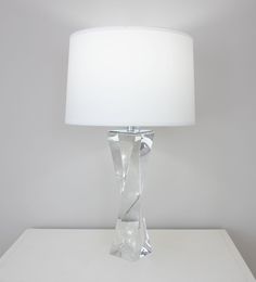 a white lamp sitting on top of a table next to a white wall and floor