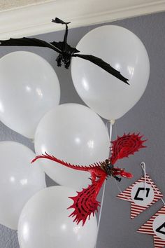 some white balloons are hanging from the ceiling with black and red decorations on them,