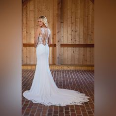 a woman in a white wedding dress standing on a brick floor with her back to the camera