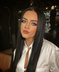 a woman with long black hair wearing a white shirt and brown tie, posing for the camera