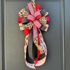 a red, white and black bow hangs on the front door's gray door