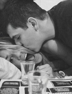 a man kissing a woman on the cheek in front of a table full of drinks