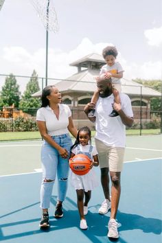 a man, woman and child are standing on a basketball court with an orange ball