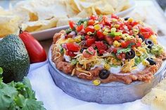 a platter filled with nachos and chips next to other foods on a table