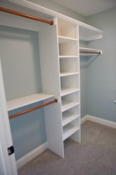 an empty walk in closet with white shelves