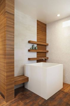 a white bath tub sitting on top of a wooden floor next to a shelf filled with bottles