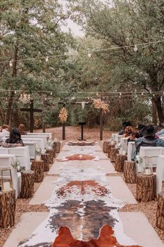 an outdoor ceremony is set up with white chairs and brown cowhides on the ground