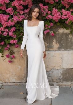 a woman standing in front of pink flowers wearing a white wedding dress with long sleeves