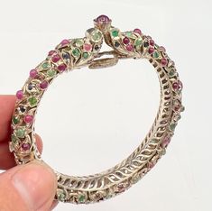 for your consideration,AZ jewelry supply present this unique vintage sterling silver dragon head bangle with genuine rubies, emeralds and sapphire in the setting the bracelet is not signed but test positive for sterling  It consist of an open work sterling silver ornate design with two dragon heads looking at each other.it is a hinged bracelet with a safety clip  the circumference is 6 1/2 inches width 3/4 inch.  this is a unique old  vintage piece and the genuine stones are present but it is a very delicate piece . it is a great piece for your collection but due to its age we caution to wear with care.  the weight is 46 grams We are a brick and mortar jewelry supply and crystal shop in Huntington Beach, Ca. We are dealers at the Tucson Gem and Mineral Show.we have a high variety of hand m Antique Jeweled Bangle Jewelry, Antique Jeweled Bangle, Silver Jeweled Fine Jewelry, Fine Silver Jeweled Jewelry, Unique Jeweled Bangle Jewelry, Unique Round Jeweled Jewelry, Unique Collectible Jeweled Jewelry, Ornate Gemstone Bangle Jewelry, Ornate Multi-stone Round Jewelry