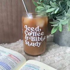 an open book sitting on top of a table next to a glass filled with liquid