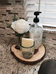 a soap dispenser and some flowers on a wood slice