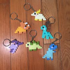 four perler keychains made to look like animals on a wooden floor,