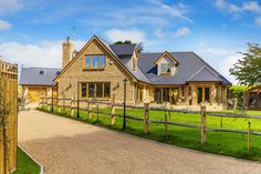 a large house with a driveway leading to the front door and side entrance that has a fenced in area next to it