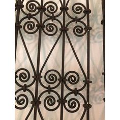 an iron gate with swirls and scrolls on the top, against a white background